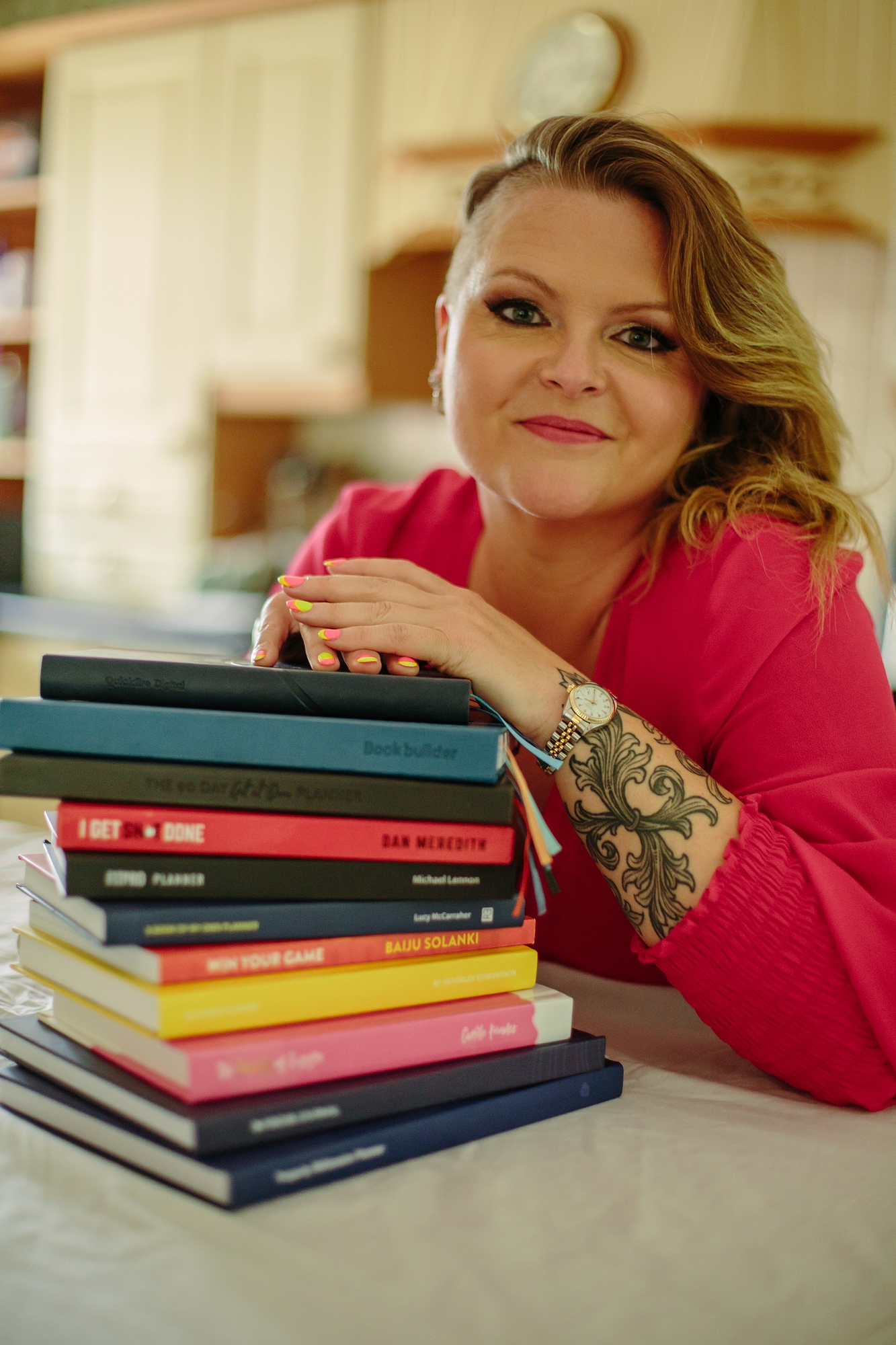Sophie leaning on a stack of planners and journals she has published