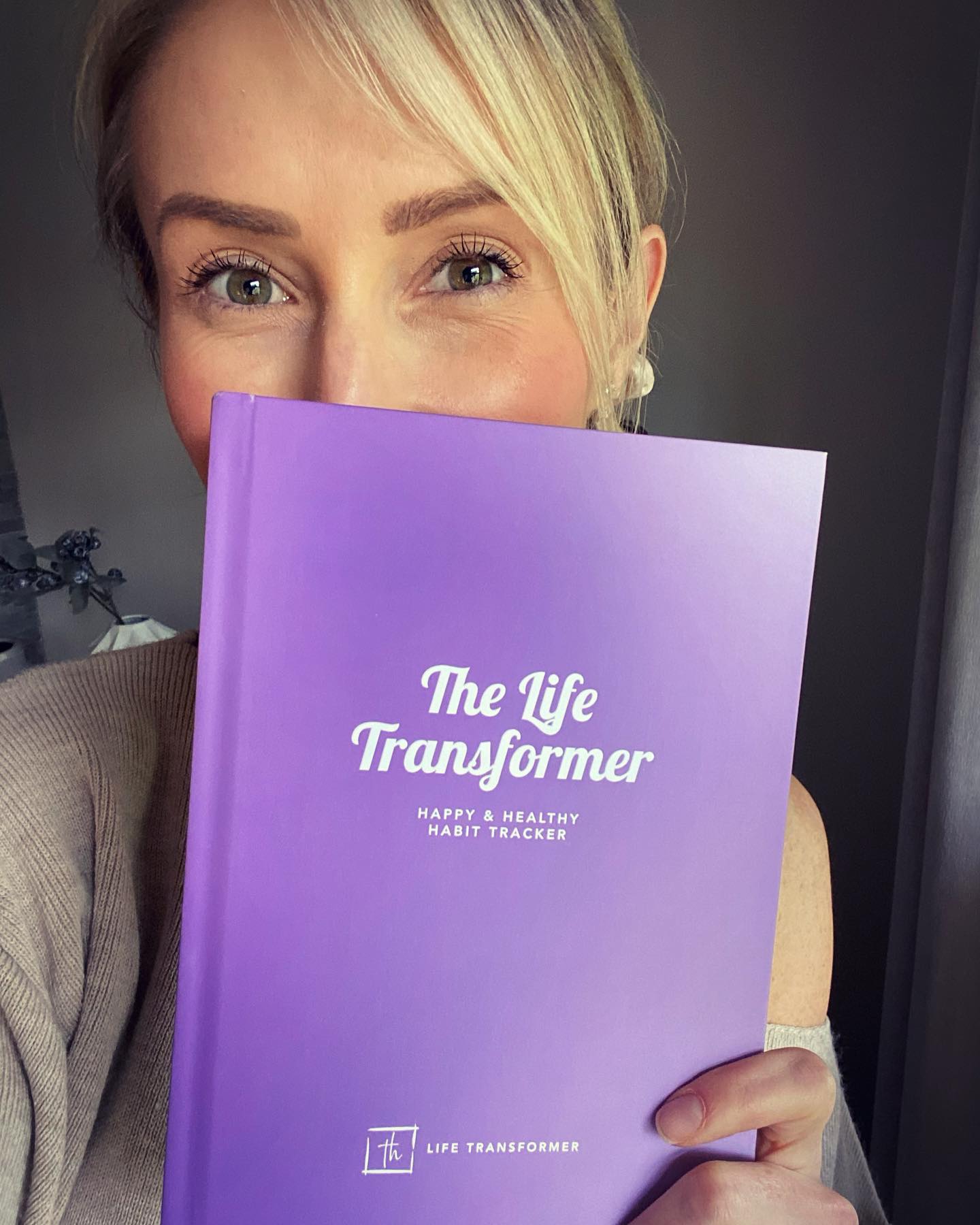 Sophie holding The Life Transformer happy and healthy habit tracker
