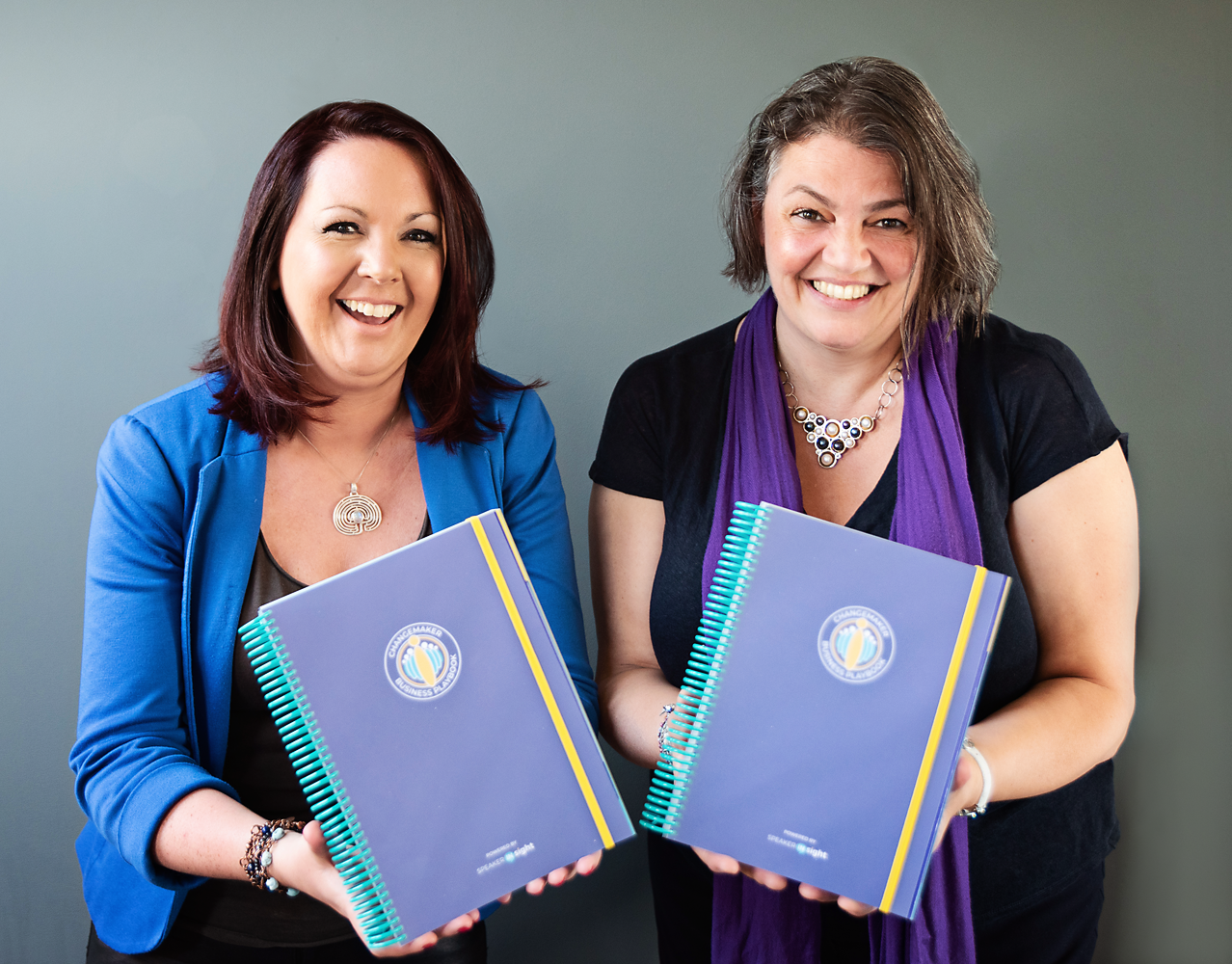 Two women holding the Changemaker Business Playbook